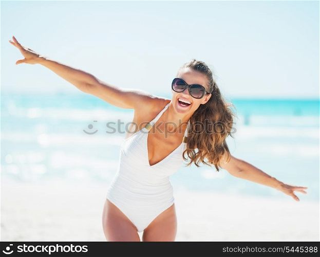 Happy young woman in swimsuit having fun time on beach