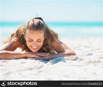 Happy young woman in swimsuit laying on beach