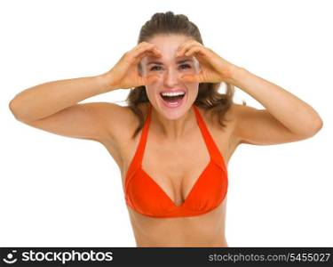 Happy young woman in swimsuit looking through binoculars shaped hands