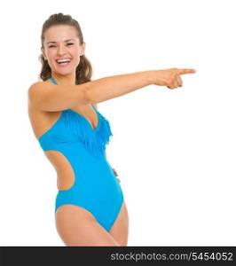 Happy young woman in swimsuit pointing on copy space