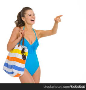 Happy young woman in swimsuit pointing on copy space