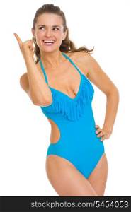 Happy young woman in swimsuit pointing up on copy space
