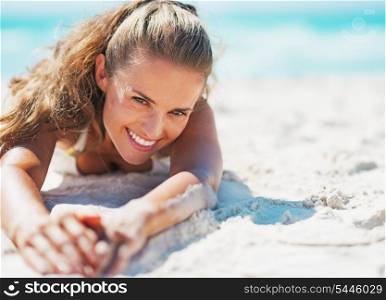 Happy young woman in swimsuit relaxing on beach