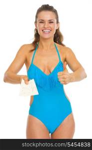 Happy young woman in swimsuit showing air tickets and thumbs up
