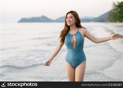 happy young woman in swimsuit walking on the sea beach at Koh Chang island, Thailand