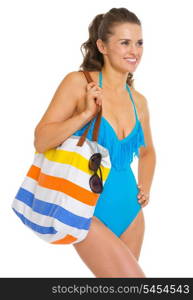Happy young woman in swimsuit with beach bag looking on copy space