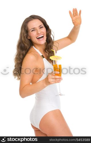 Happy young woman in swimsuit with cocktail saluting