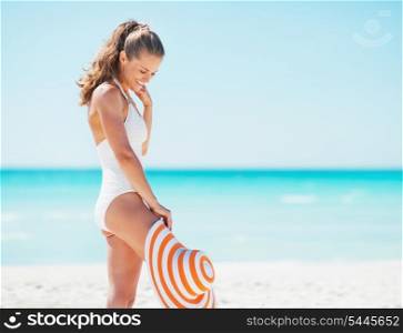 Happy young woman in swimsuit with hat enjoying on beach
