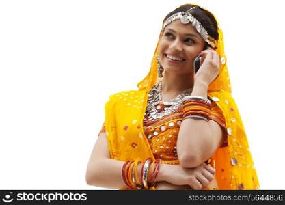 Happy young woman in traditional wear using mobile phone against white background