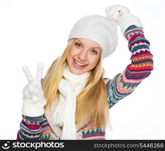 Happy young woman in winter clothes showing victory gesture