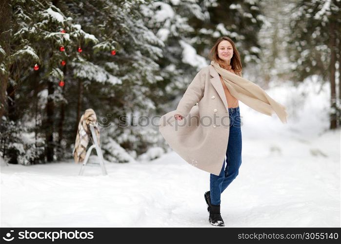 happy young woman in winter day outdoors in forest. background of tree branches in the snow and decorated with Christmas decorations. happy young woman in winter day outdoors in forest. background of tree branches in the snow and decorated with Christmas decorations.