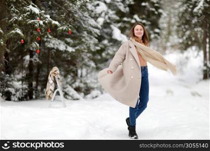 happy young woman in winter day outdoors in forest. background of tree branches in the snow and decorated with Christmas decorations. happy young woman in winter day outdoors in forest. background of tree branches in the snow and decorated with Christmas decorations.
