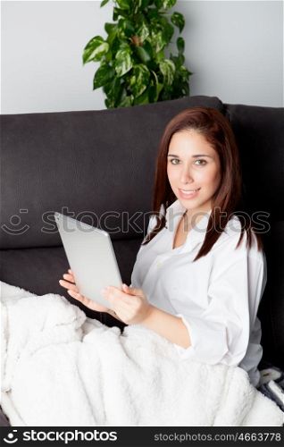 Happy young woman is relaxing on comfortable couch and using tablet at home. &#xA;