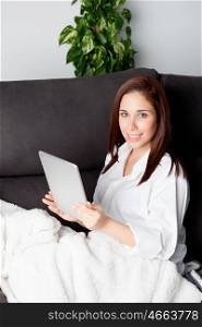 Happy young woman is relaxing on comfortable couch and using tablet at home. &#xA;