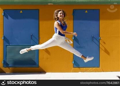 Happy young woman jumping in urban background. Gen Z girl. Happy young woman jumping in urban background