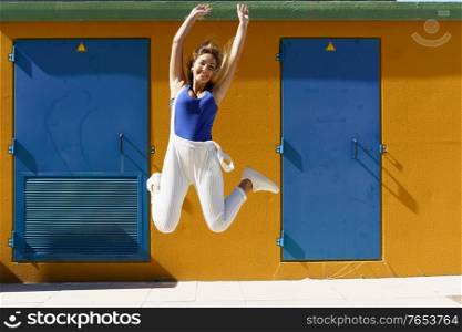 Happy young woman jumping in urban background. Gen Z girl. Happy young woman jumping in urban background