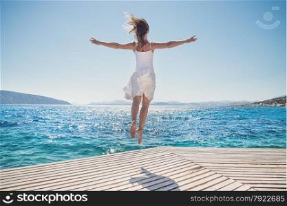 Happy young woman jumping on the beach