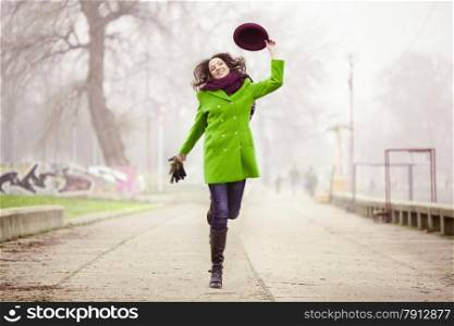 Happy Young Woman Jumping with a Hat at the Footpath in the Foggy Day