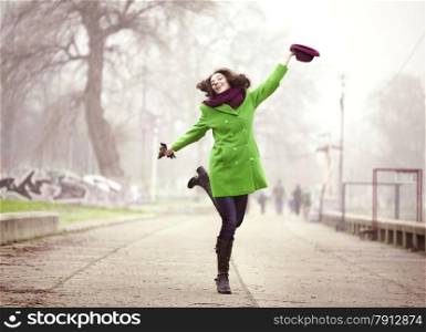 Happy Young Woman Jumping with a Hat at the Footpath in the Foggy Spring Day