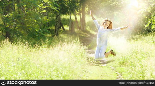 Happy Young Woman Jumping with Raised Arms at the Green Meadow.