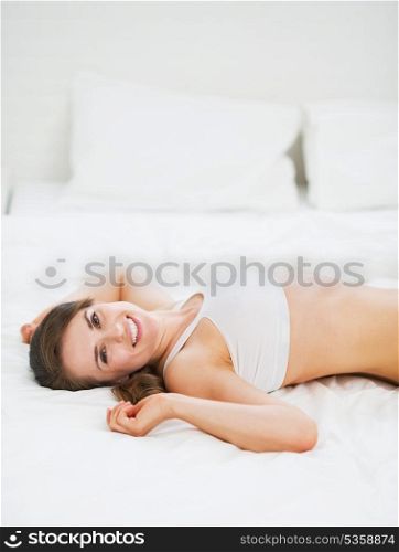 Happy young woman laying in bed