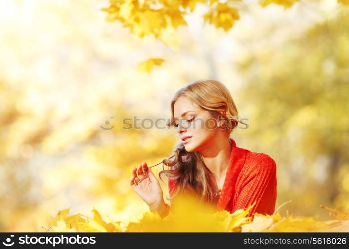 Happy young woman laying on autumn leaves in park