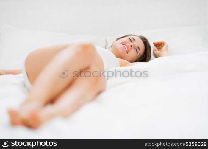 Happy young woman laying on bed