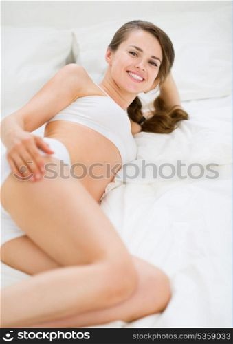 Happy young woman laying on bed