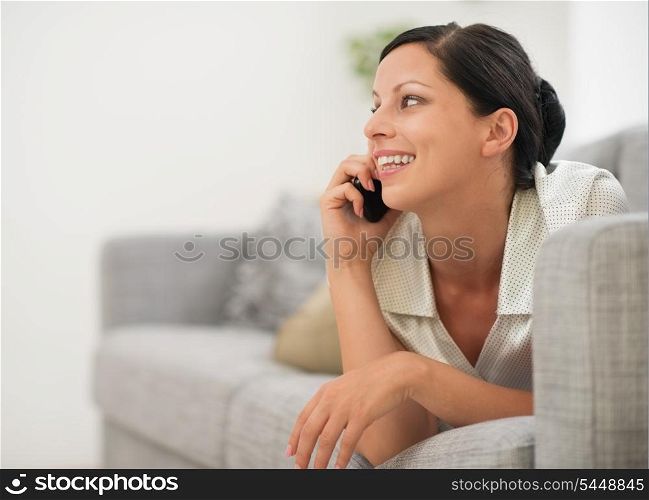 Happy young woman laying on sofa and speaking cell phone