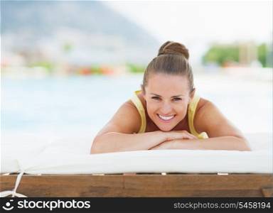 Happy young woman laying on sunbed