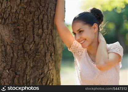 Happy young woman lean against tree