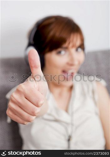 Happy young woman listening music with thumbs up