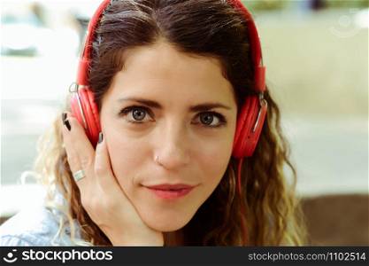 Happy young woman listening to music with headphones in the street. Summer lifestyle.