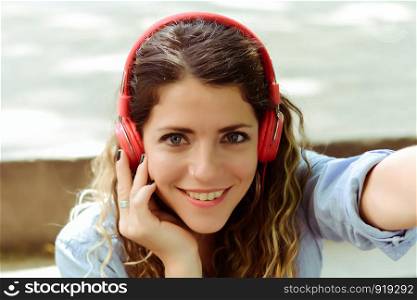 Happy young woman listening to music with headphones in the street. Summer lifestyle.