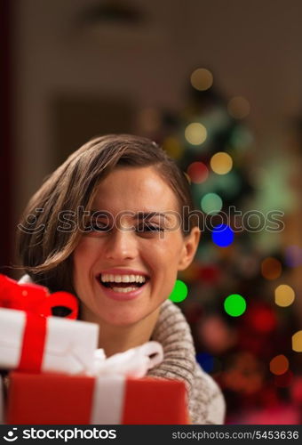 Happy young woman looking out from Christmas gift boxes