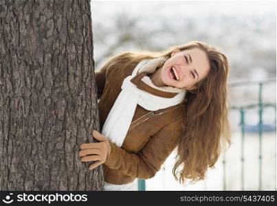 Happy young woman looking out from tree