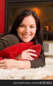 Happy young woman lying on rug by fireplace home living