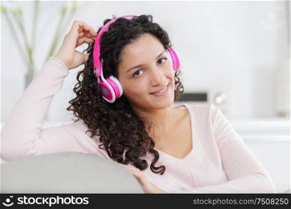happy young woman lying on sofa with earphones