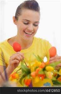 Happy young woman making Easter decoration with tulips and eggs