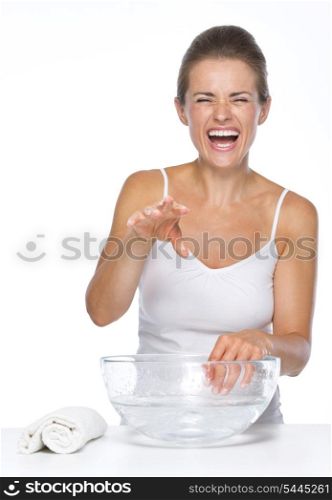 Happy young woman making fun while washing hands in glass bowl with water
