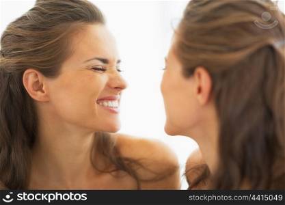 Happy young woman making funny face in mirror