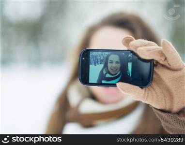 Happy young woman making self photo in winter outdoors