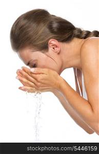 Happy young woman making water splashes while washing face