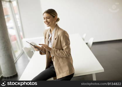 Happy young woman manager holding digital tablet and standing in modern office