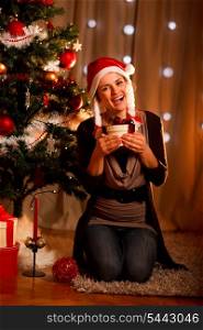 Happy young woman near Christmas tree hugging present box&#xA;