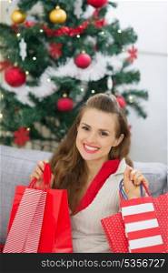 Happy young woman near Christmas tree with shopping bags