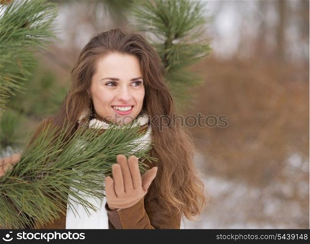 Happy young woman near fir-tree looking on copy space