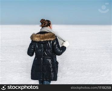 Happy, young woman on a background of a snowy field on a clear, sunny day. Happy woman on a background of a snowy field