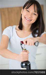 happy young woman opens a wine bottle