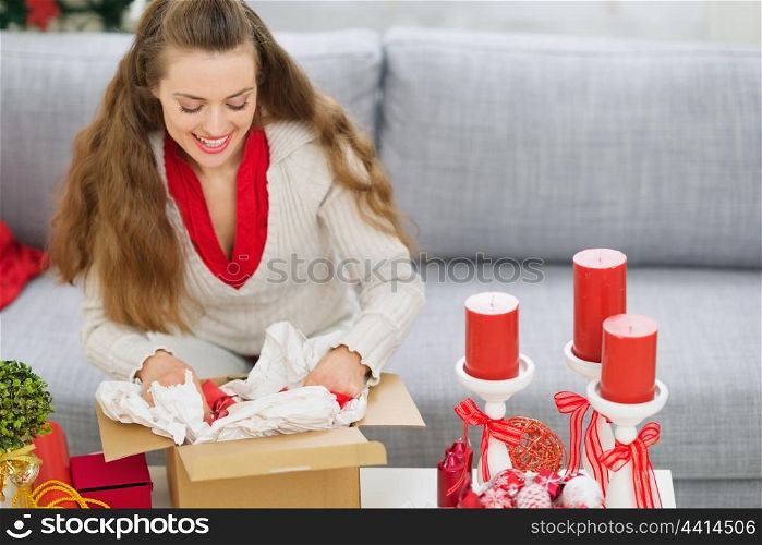 Happy young woman packing parcel with Christmas gift